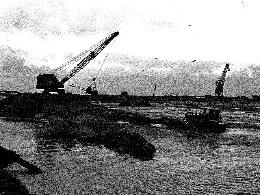 A grainy black-and-white image of steam shovels scooping dirt near water.