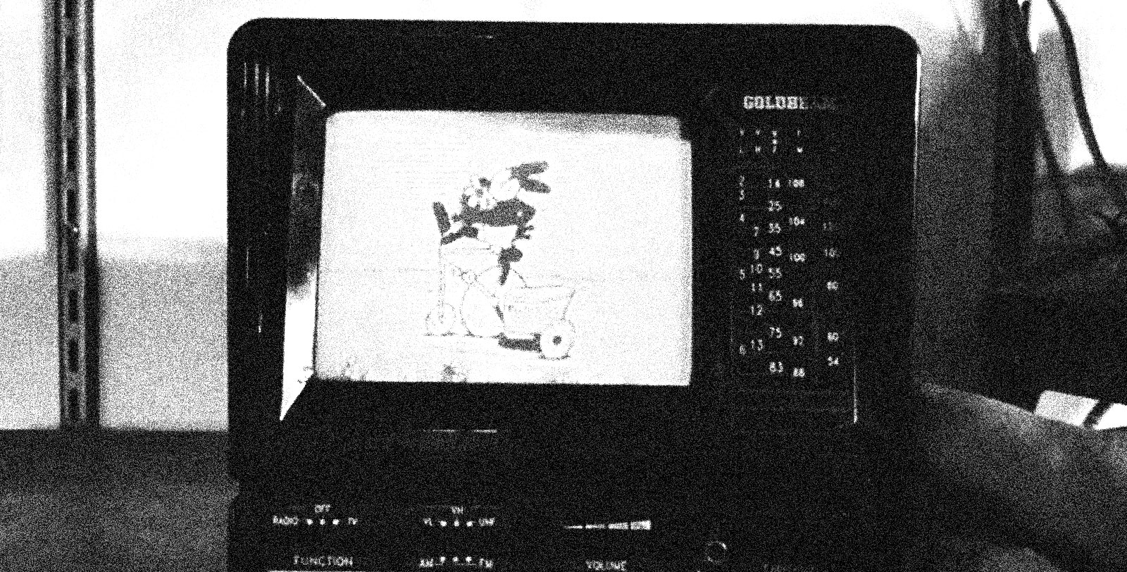 A grainy black-and-white image of a small TV showing a cartoon rabbit on a bicycle